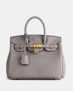 Bolso de cuero MILA de Veyro Madrid, en color marrón, con asas cortas y cierre metálico, sobre fondo neutro.